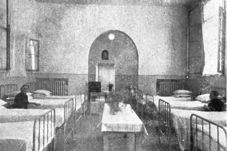 Foto storica reparto ospedaliero storico con letti in ferro e tavolo centrale